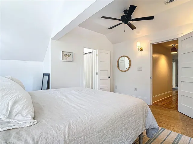 Bedroom featuring visible vents, baseboards, wood finished floors, a ceiling fan, and vaulted ceiling