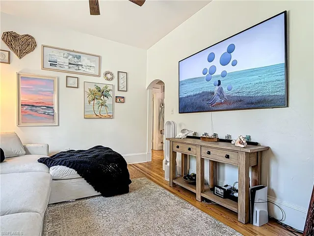 Living room featuring arched walkways, baseboards, wood finished floors, and a ceiling fan