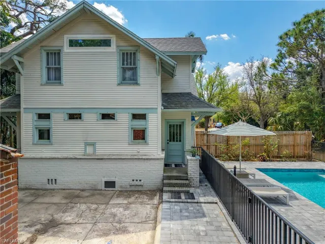 Rear view of property featuring a fenced backyard, a fenced in pool, a shingled roof, and a patio area