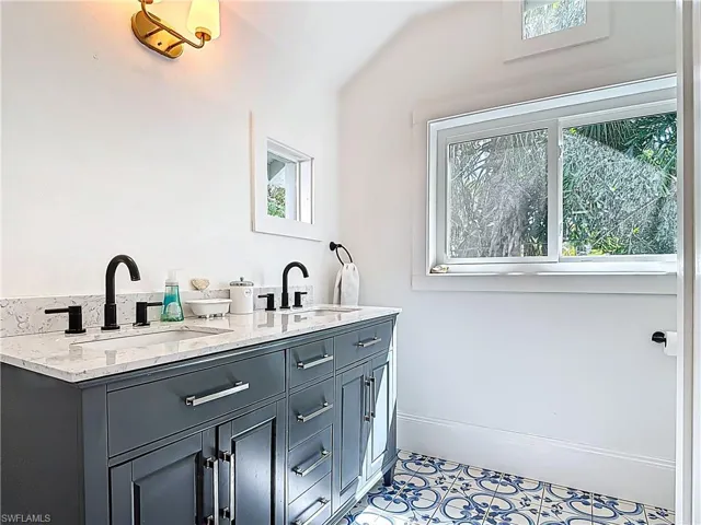 Full bath with baseboards, double vanity, and a sink