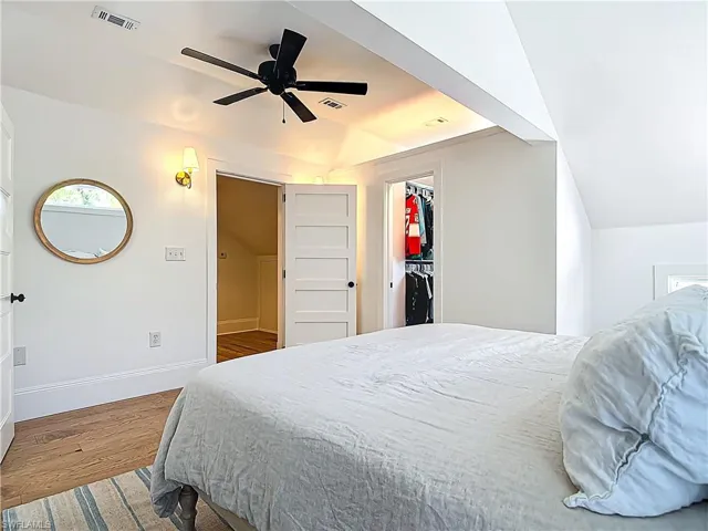 Bedroom with baseboards, visible vents, wood finished floors, and vaulted ceiling