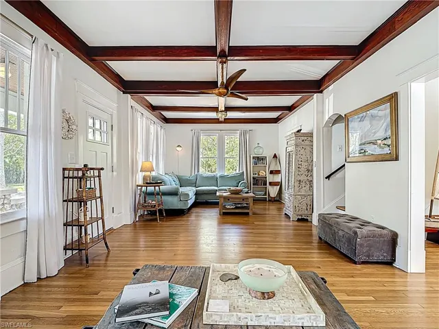 Living room with beamed ceiling, ceiling fan, and light wood-type flooring