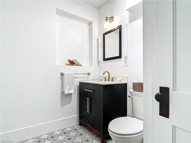 Half bathroom featuring baseboards, toilet, and vanity