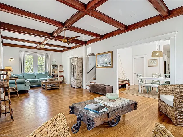 Living room featuring coffered ceiling, stairway, beamed ceiling, light wood-style floors, and ceiling fan