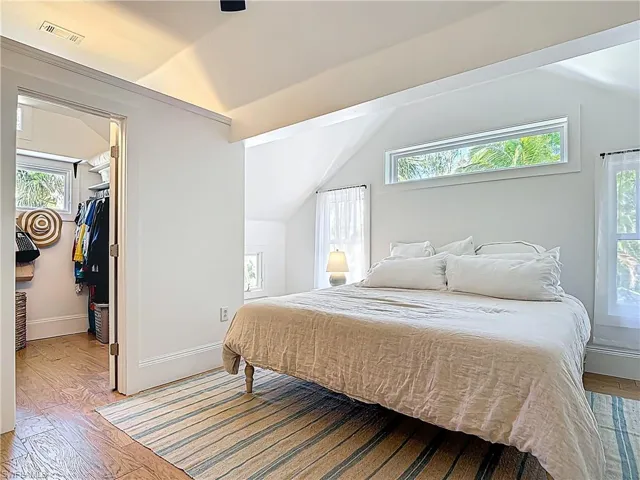 Bedroom featuring a spacious closet, light wood-style floors, vaulted ceiling, and visible vents