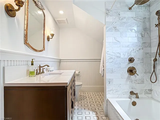 Full bath featuring toilet, vanity, bathing tub / shower combination, wainscoting, and visible vents