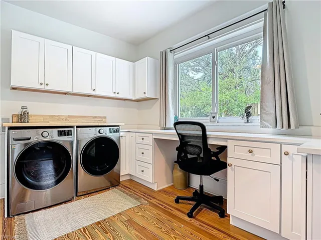Washroom with cabinet space, independent washer and dryer, and light wood-type flooring