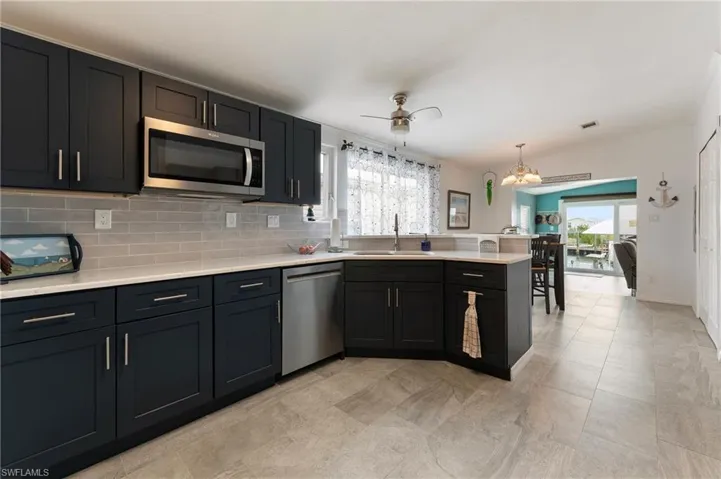 Kitchen featuring stainless steel appliances, a peninsula, plenty of natural light, tasteful backsplash, and ornamental molding