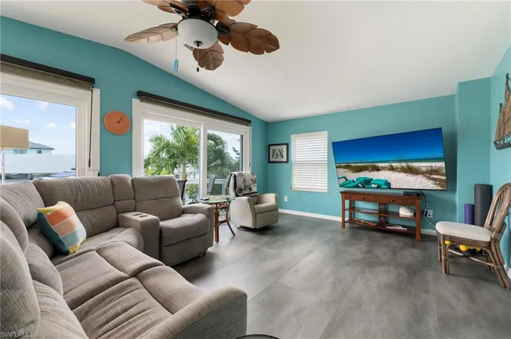 Florida room with vaulted ceiling, a ceiling fan, and concrete look laminate floors