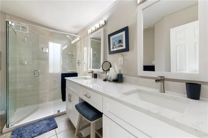 Full bath featuring double vanity, a stall shower, and light tile patterned floors