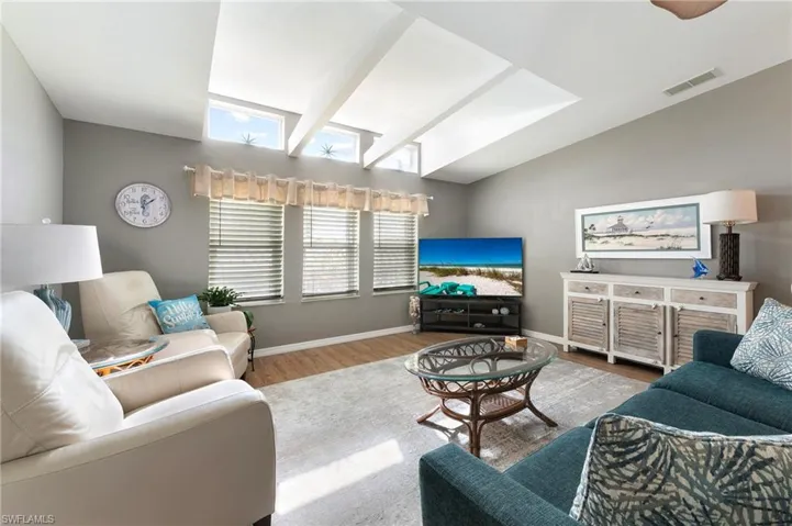 Living area with wood finished floors, skylights and vaulted ceiling