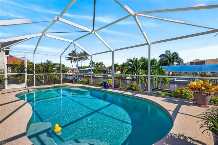 Screened outdoor swimming pool with integrated steps, surrounded by a textured concrete deck