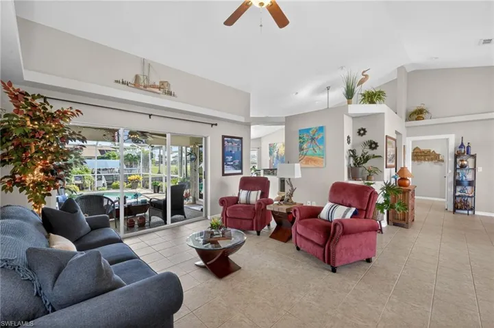 Spacious living area featuring neutral-toned tile flooring, vaulted ceilings, and a ceiling fan