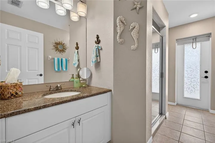 Bathroom vanity featuring a built-in sink, stone-finish countertop, and white cabinetry