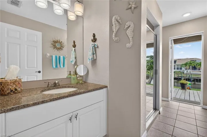 Bathroom vanity featuring a single basin sink, granite countertop, and white cabinetry