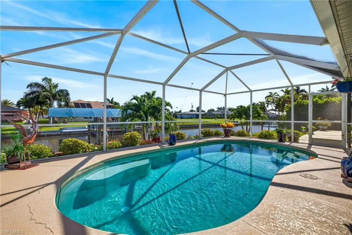 Screened lanai featuring an irregular shaped pool with integrated steps