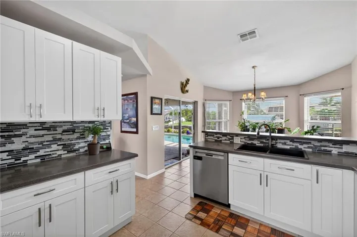 Modern kitchen with white shaker-style cabinetry, dark countertops, and a mosaic tile backsplash