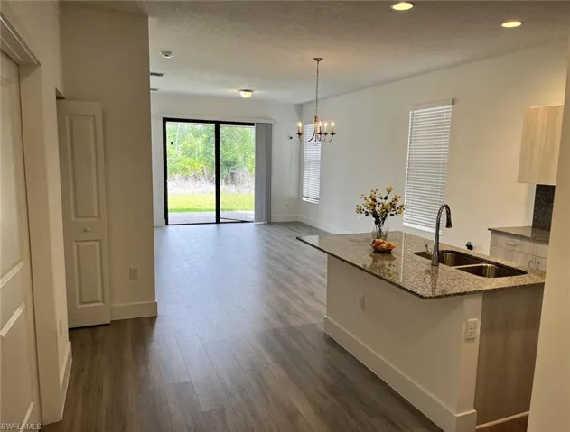 Kitchen featuring dark stone counters, decorative light fixtures, a chandelier, dark wood-style floors, and a textured ceiling