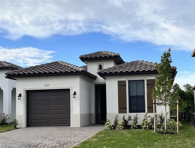 View of front of home featuring a garage, decorative driveway, stucco siding, a front yard, and a tiled roof