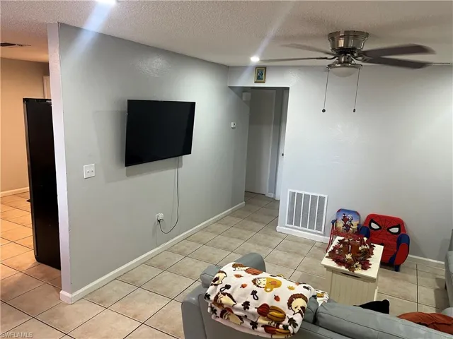 Game room with a textured ceiling, light tile patterned floors, and ceiling fan