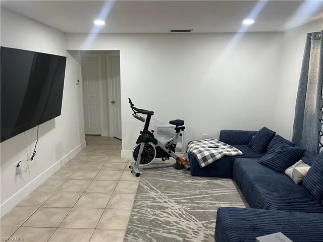 Living room with light tile patterned floors and recessed lighting