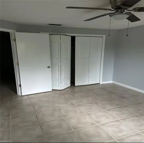 Unfurnished bedroom featuring a closet, a ceiling fan, and light tile patterned floors