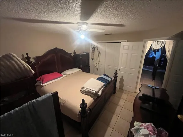 Tiled bedroom featuring a closet, a ceiling fan, and a textured ceiling