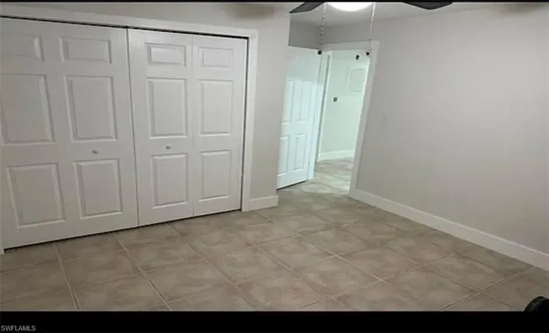 Unfurnished bedroom with a closet, a ceiling fan, and light tile patterned floors