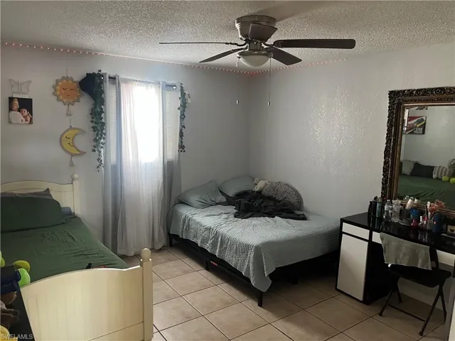 Bedroom with light tile patterned floors, a textured ceiling, and a ceiling fan