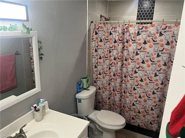 Full bath with a textured wall, a shower with shower curtain, and vanity