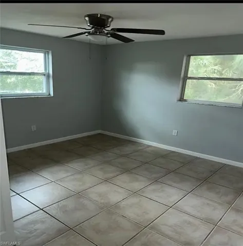 Empty room with light tile patterned floors and a ceiling fan