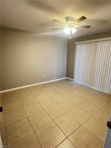 Empty room with a ceiling fan and light tile patterned floors