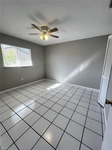 Empty room featuring a ceiling fan and tile patterned floors