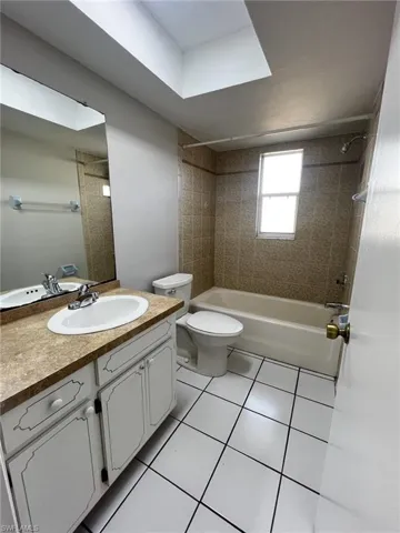 Bathroom with tub / shower combination, vanity, and light tile patterned floors