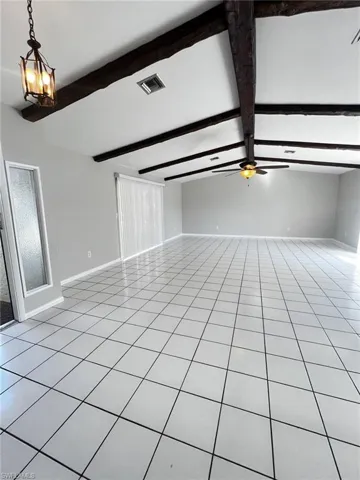 Unfurnished living room featuring light tile patterned floors and beam ceiling