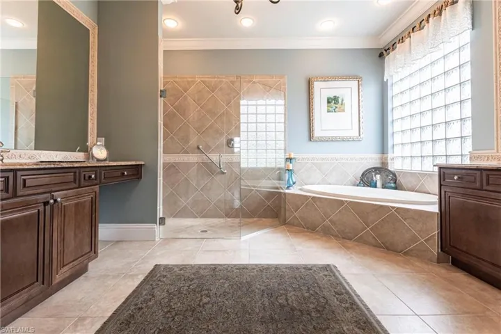 Bathroom featuring vanity, a garden tub, ornamental molding, light tile patterned floors, and walk in shower