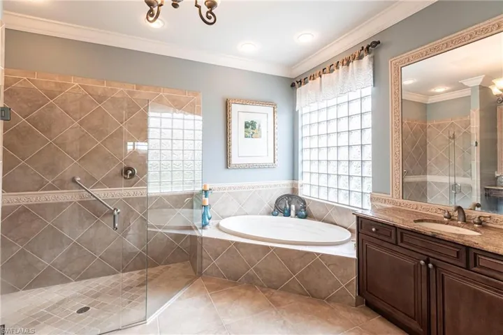 Full bath featuring a stall shower, healthy amount of natural light, a bath, crown molding, and vanity
