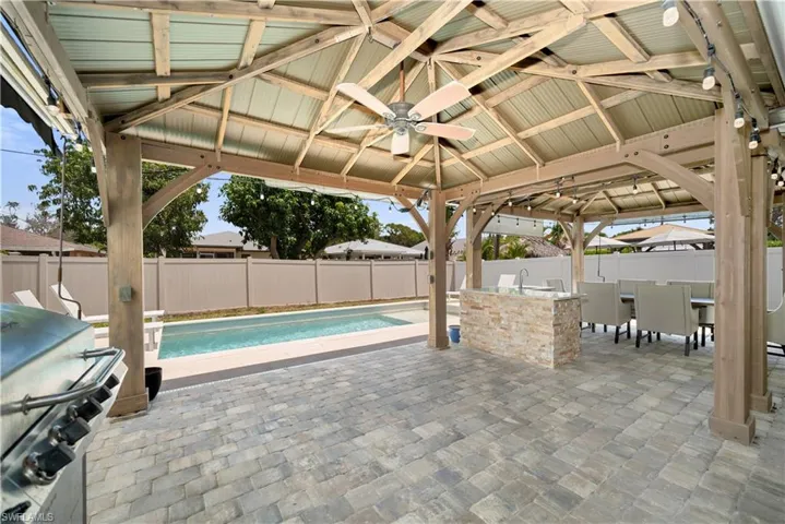 Fenced backyard featuring a gazebo, ceiling fan, a patio, and grilling area