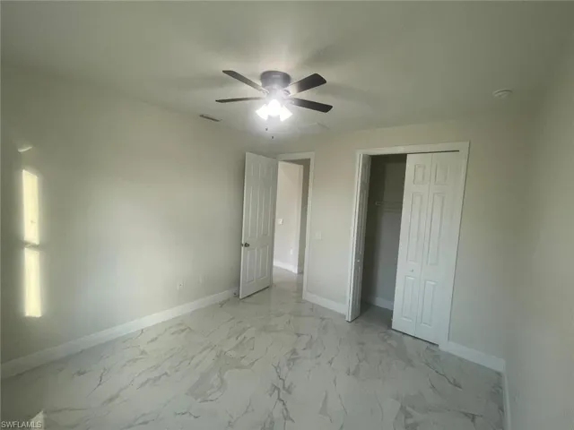 Unfurnished bedroom with ceiling fan, a closet, and light tile flooring