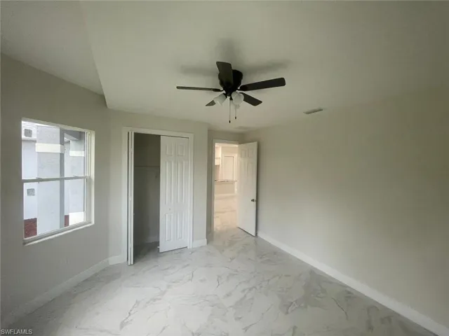 Unfurnished bedroom with ceiling fan, a closet, and light tile floors