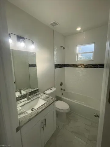 Full bathroom featuring tile floors, oversized vanity, toilet, and tiled shower / bath combo