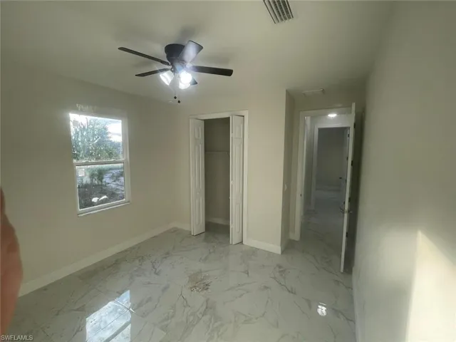 Unfurnished bedroom with a closet, light tile flooring, and ceiling fan