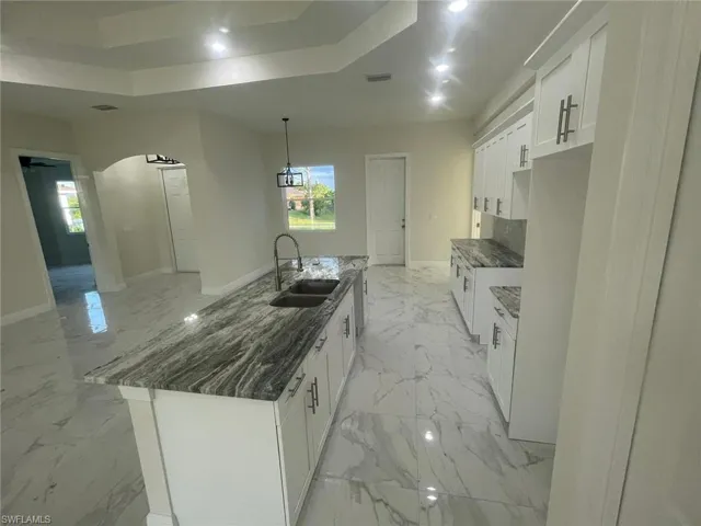 Kitchen with sink, a kitchen island with sink, and light tile floors