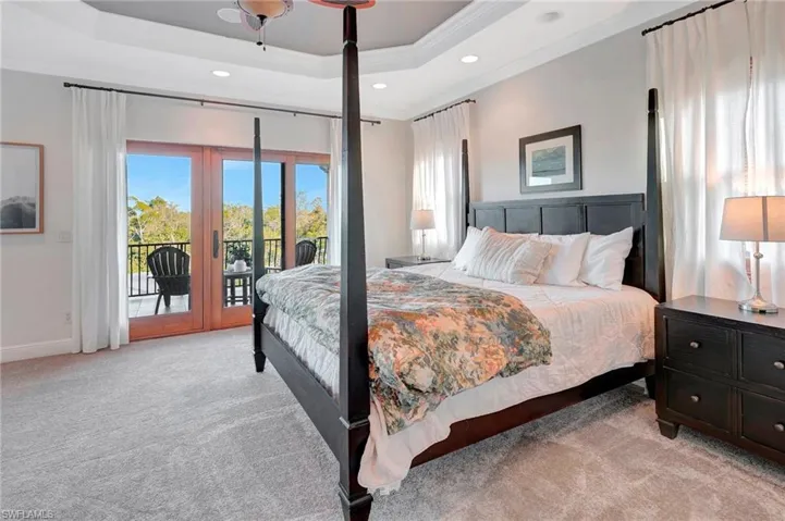 Bedroom with light carpet, access to exterior, a tray ceiling, and french doors