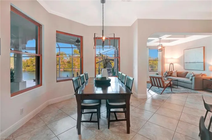 Dining area with crown molding, coffered ceiling, light tile patterned floors, and a wealth of natural light