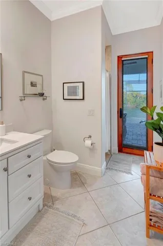 Bathroom with toilet, tile patterned flooring, vanity, walk in shower, and crown molding