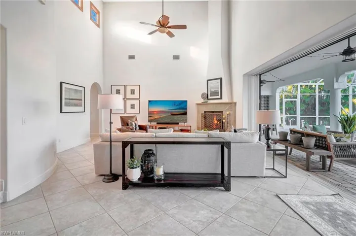 Living room with ceiling fan, a high ceiling, and light tile patterned floors