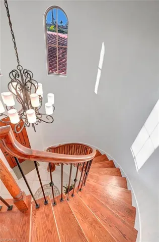 Stairway with hardwood / wood-style flooring and an inviting chandelier