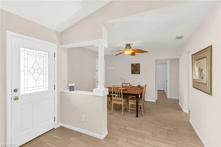 Foyer entrance with light wood-style flooring, visible vents, baseboards, vaulted ceiling, and a ceiling fan