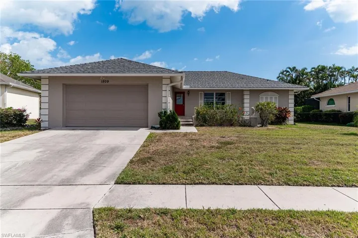 Single story home featuring a front yard, driveway, an attached garage, and stucco siding